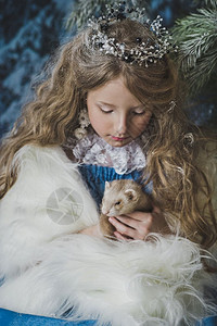 公主手上拿着一只活的雪貂圣诞树上的孩子手拿着雪貂4579图片