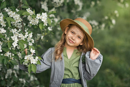 在樱花边穿着漂亮裙子的快乐女孩178年樱花间戴帽子的孩一幅大肖像图片