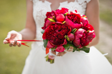 穿着婚纱的新娘手里有一束红色的花285年的一位女孩手里有束亮的红色花束图片