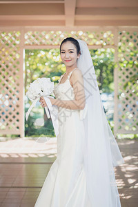 在婚礼当天美丽的年轻女子穿着白色礼服在花园里公的女肖像图片