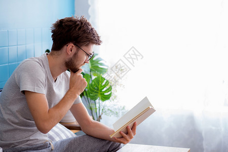 年轻人戴眼镜在客厅沙发上阅读书图片
