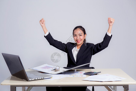 利用计算机在办公室工作的年轻女商人和对成功表示高兴的手势集中妇女在线搜索信息图片
