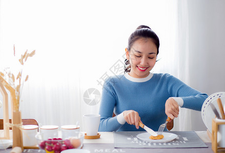 漂亮的女人拿着勺子刀在厨房里吃食物背景图片