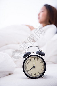 站在床边桌的闹钟清晨会响起来唤醒睡在床上的女人背景中睡觉早不着觉得到工作时间概念图片
