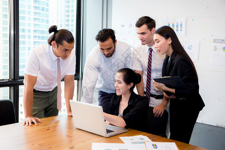 商业团队在会议期间使用笔记本电脑开会并介绍情况背景图片