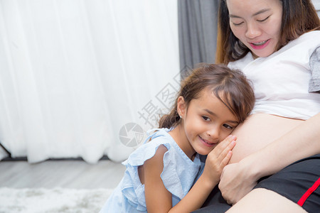 小孩在肚子里倾听婴儿的声音拥抱母亲在房间里充满幸福图片