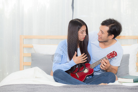 年轻的亚裔夫妇在卧室里玩着四轮式的放松快乐地享受着幸福图片