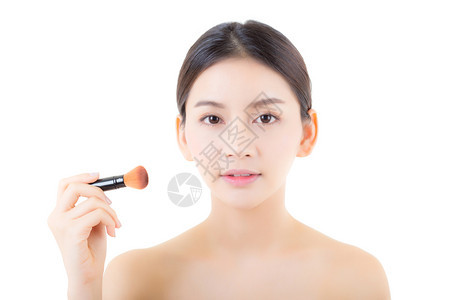 美貌的亚裔女申请用白色背景健康清洁皮肤概念上隔绝的刷子补妆图片