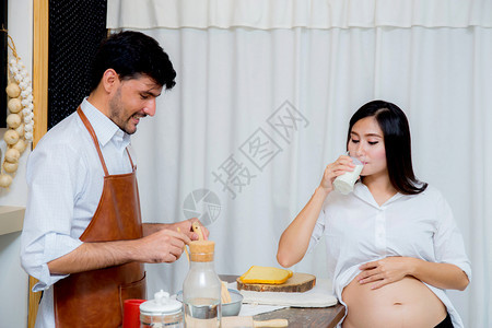 怀孕妻子的在厨房喝牛奶图片