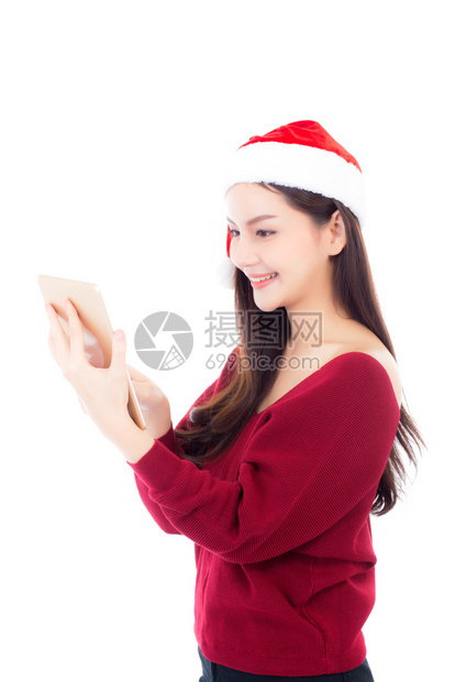 穿着红色礼服戴圣诞帽的美丽年轻女手持白衣的石板与色背景隔绝女孩与数字连接通信概念图片