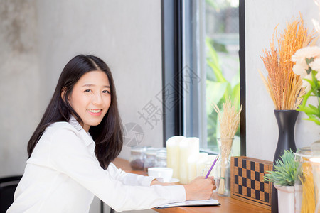 美丽的商业女青年在桌子上的笔记本写作女孩在咖啡店工作自由职业概念图片