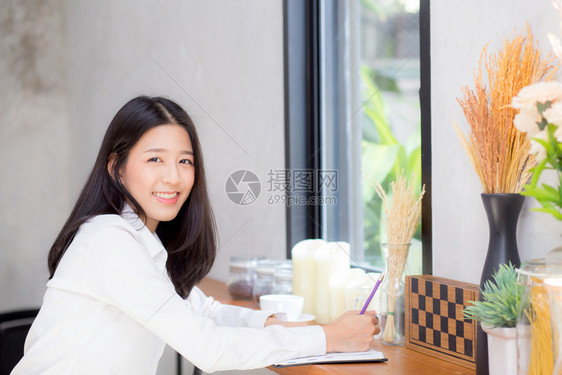 美丽的商业女青年在桌子上的笔记本写作女孩在咖啡店工作自由职业概念图片