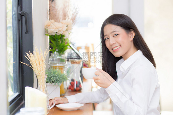 美丽的年轻女在咖啡馆喝早上微笑女孩坐在咖啡店吃早餐图片