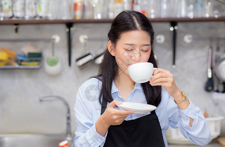 美丽的年轻咖啡师肖像喝咖啡亚裔妇女是一名雇员站在柜台咖啡店服务概念图片