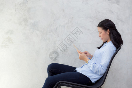 美丽的年轻女触摸平板电脑坐在水泥背景上微笑自由职业女打电话通信概念图片