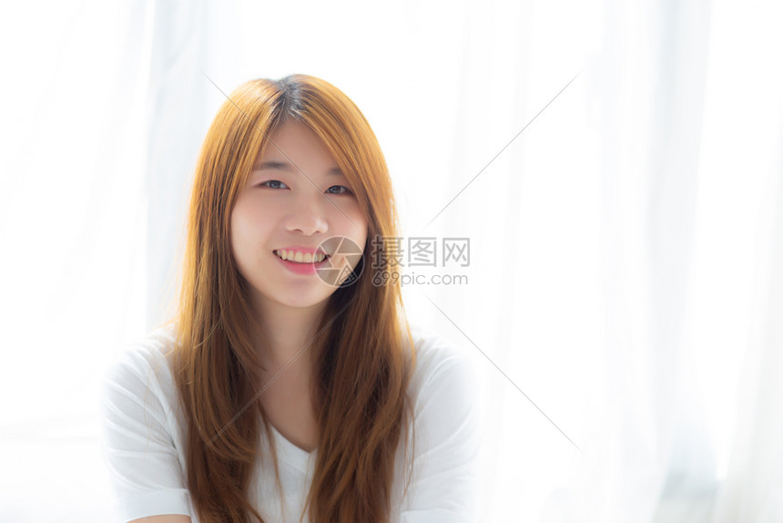 美丽的年轻亚洲女人肖像站在窗边微笑早上醒来时清晨的日出生活方式和放松的概念图片