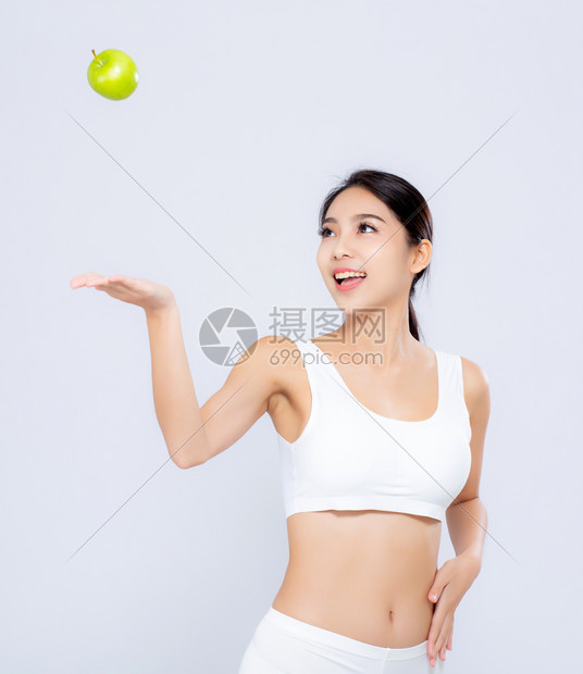 长得像的亚洲妇女微笑着扔绿色苹果和美丽的身体饮食图片