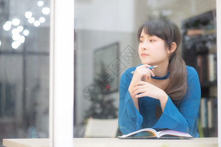 美丽的肖像年轻的亚洲女作家微笑着思考的想法和写在笔记本或日记上的快乐亚洲女孩的生活方式是学生女规划工作教育和商业观念图片