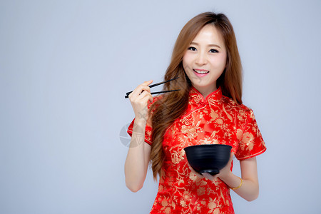 美丽的肖像年轻亚洲女穿着红青山拿筷子和碗孤立在白色背景新年假期的概念背景图片