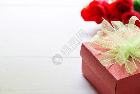 赠送红玫瑰花和礼物盒木制桌边有弓丝带2月14日爱浪漫的情人节概念图片