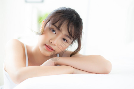 年轻的亚洲女人放松躺着的睡眠和微笑早上醒来时日出睡房里快乐和的女孩健康与的概念图片