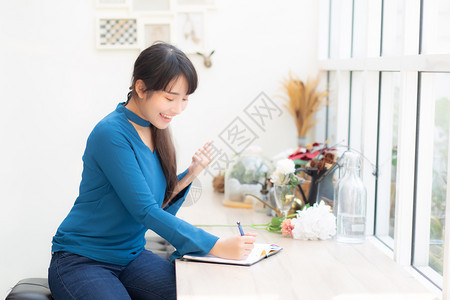 美丽的肖像亚洲女作家兴奋地写在笔记本或日记上与成功和快乐生活方式亚洲女孩是学生女计划工作教育和商业理念图片