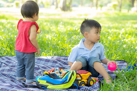 小男孩和女正在玩想法和灵感与玩具块小孩学习与建筑块教育儿童活动和游戏在公园的建筑块在夏季快乐的公园图片