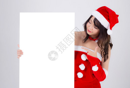 美丽的年轻圣诞老人女子拿着空白板为背景孤立的XmasAsia女孩展示空的标语纸海报并指向圣诞节假日和新年的广告背景图片