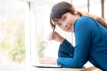 年轻女作家在笔记本或日上微笑着思考想写快乐Asia女孩的生活方式是学女规划工作教育和商业概念图片