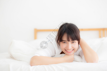 美丽的肖像年轻亚洲女人说谎和微笑早晨醒来时日出女孩在卧室里快乐的安得生活方式和放松概念图片