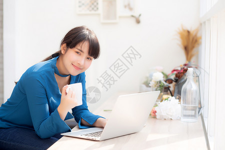 美丽的年轻自由职业女利用笔记本和喝咖啡商业与生活方式概念与专业的Asia女孩一起在办公咖啡厅微笑工作并使用笔记本电脑和图片