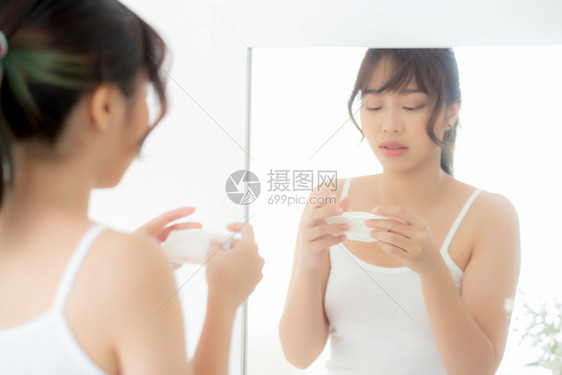 美丽的肖像年轻女微笑与皮肤护理化妆品使用油抹纸在脸上看着镜子房间的中美Asia女孩擦和清洗化妆品与组织清洁的面部概念图片