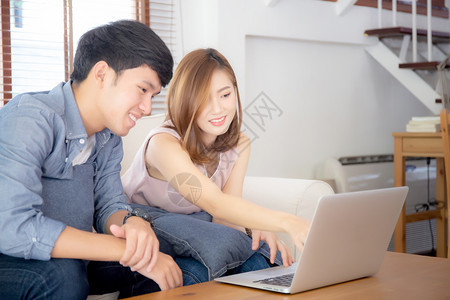 使用笔记本电脑思考和搜索互联网的亚洲年轻夫妇图片