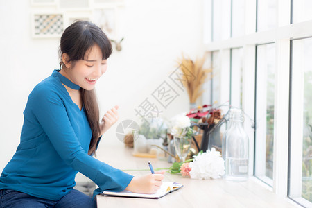 美丽的肖像亚洲女作家兴奋地写在笔记本或日记上与成功和快乐生活方式亚洲女孩是学生女计划工作教育和商业理念图片