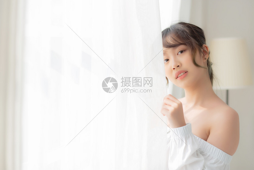 美丽的年轻亚洲女站在窗户边微笑早上醒来时日出女孩对新鲜欢乐生活方式和放松概念感到快乐图片