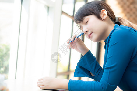 年轻女作家在笔记本或日上微笑着思考想写快乐Asia女孩的生活方式是学女规划工作教育和商业概念图片