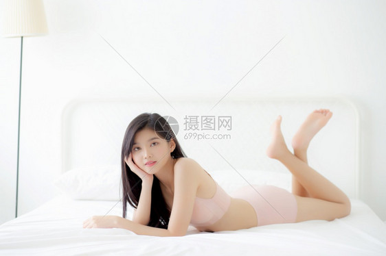 穿着内衣感的年轻女美丽肖像与卧室的诱惑相适应衣物内中瘦弱的Asia女孩身躯自信和快乐地躺在床上睡房里生活方式概念图片