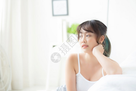 美貌丽的年轻女微笑早上起床时醒来健康美貌女孩在床上快乐地躺皮肤上卧室化妆品生活方式和放松概念图片