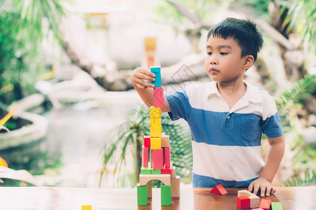 亚洲小男孩玩木制具以创造和发展为桌上的木制玩具享受快乐的孩子学习活动游戏技巧在家桌上玩游戏时学习创意教育概念图片