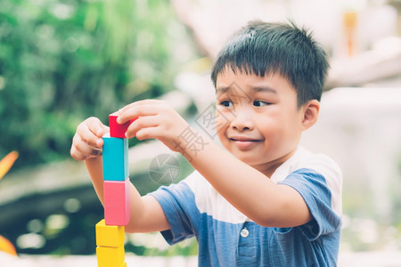 亚洲小男孩玩木制具以创造和发展为桌上的木制玩具享受快乐的孩子学习活动游戏技巧在家桌上玩游戏时学习创意教育概念图片