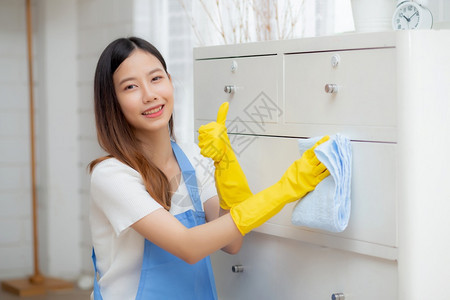 在室内做手套清洗的年轻女管家被织物女佣和服务擦去在家中的起居室务和生活方式概念中工人擦粉图片