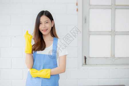 身穿橡胶手套和围裙的年轻女是家庭保护佣制服清洁和洗涤女在职工人积极一生活方式概念的女管家图片