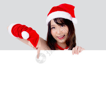 美丽的年轻圣诞老人女子拿着空白板为背景孤立的XmasAsia女孩展示空的标语纸海报并指向圣诞节假日和新年的广告图片