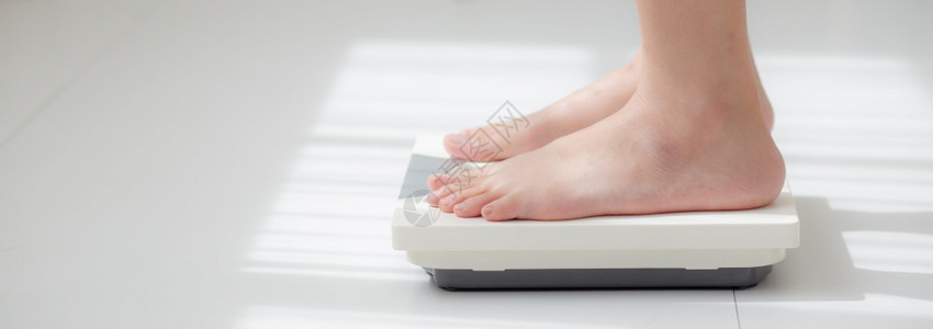 从事活动的妇女腿站着衡量体重比例与赤脚饮食近的瘦女孩减肥措施以控制食物健康护理和概念横幅网站图片