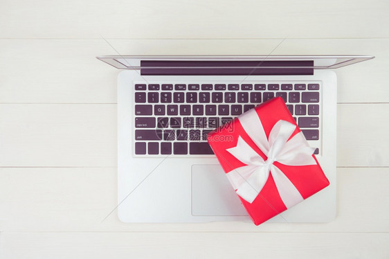 红礼盒和笔记本电脑放在木制桌子上赠送圣诞节或周年生日季节和庆祝最高视野平地在线购物概念图片
