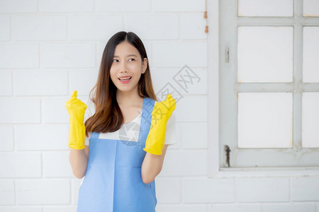 身穿橡胶手套和围裙的年轻女是家庭保护佣制服清洁和洗涤女在职工人积极一生活方式概念的女管家图片