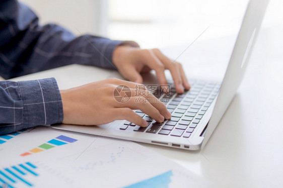 商人手在笔记本电脑上打键盘而文件数据图表营销和投资统计利润报告财政增长管理和规划图片