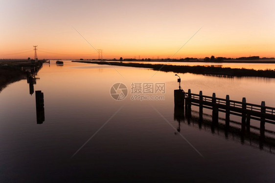 在一艘船驶近时在荷兰河上方美丽的日出图片