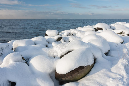 阳光明媚的一天荷兰堤坝沿线长的岩石覆盖着雪图片