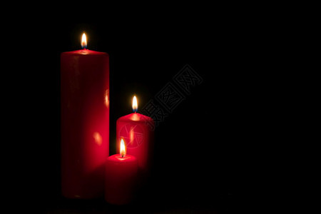 三个红蜡烛在黑暗中燃烧图片